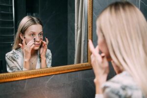 Kvinne i førtiårene som ser seg i speilet, litt bekymret.