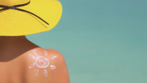 Kvinne med solhatt og solkrem på stranden.